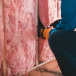 Man cutting whole in wall insulation for outlet in exposed wall